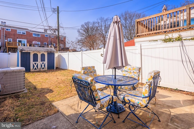 view of patio / terrace with outdoor dining area, a fenced backyard, central air condition unit, an outdoor structure, and a shed