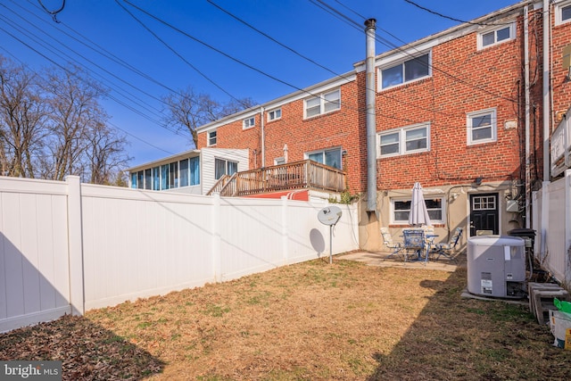 back of property featuring a yard, a fenced backyard, a patio, and brick siding