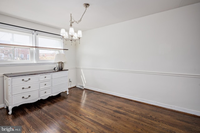 unfurnished dining area with dark wood-style floors, visible vents, and an inviting chandelier