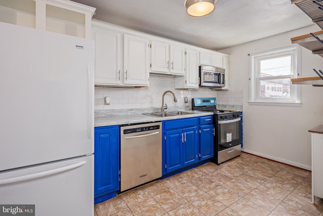 kitchen with blue cabinets, a sink, light countertops, appliances with stainless steel finishes, and decorative backsplash