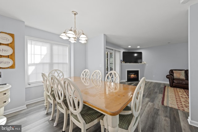 dining area featuring baseboards, a glass covered fireplace, dark wood-style floors, a chandelier, and recessed lighting