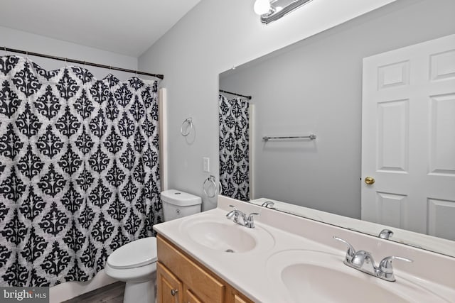 full bath with toilet, a shower with curtain, double vanity, and a sink