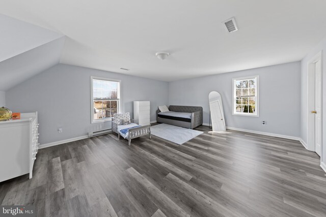 unfurnished room with a healthy amount of sunlight, visible vents, vaulted ceiling, and wood finished floors