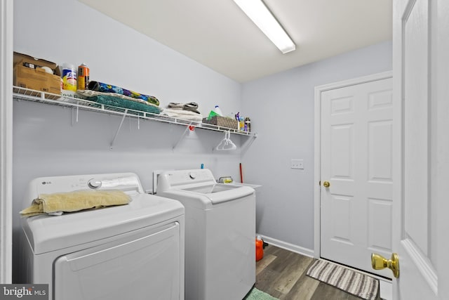 laundry area with laundry area, washing machine and dryer, baseboards, and wood finished floors