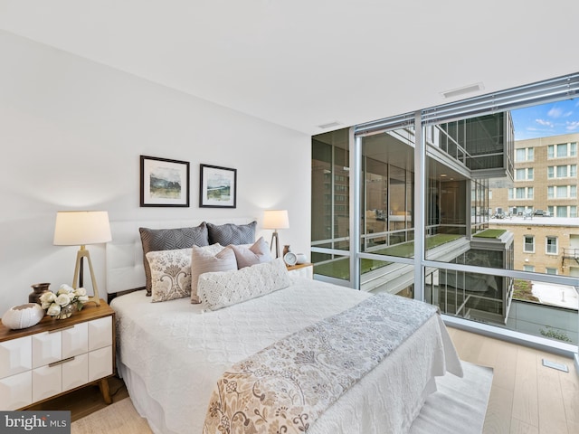 bedroom featuring expansive windows and wood finished floors