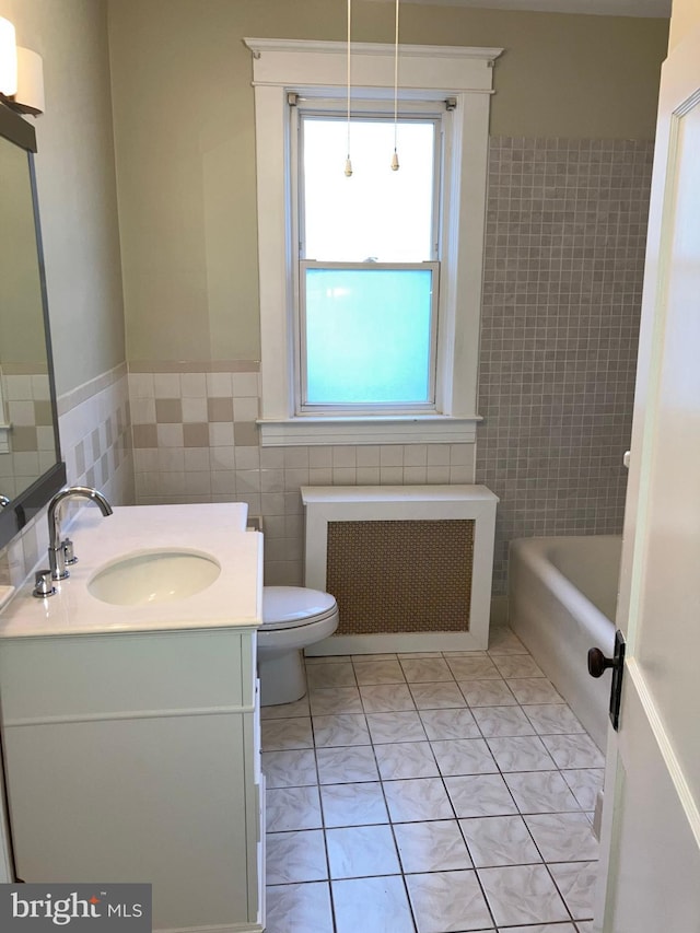 bathroom featuring radiator heating unit, tile patterned flooring, a bathtub, vanity, and tile walls