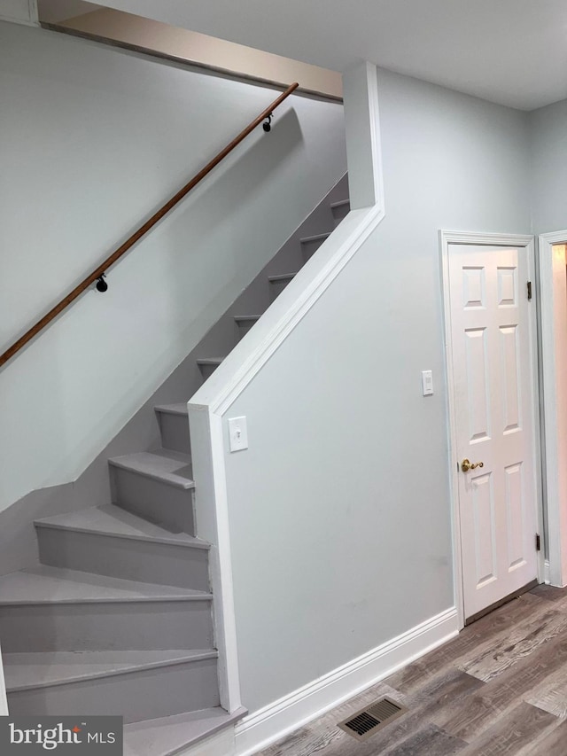 staircase featuring visible vents, baseboards, and wood finished floors