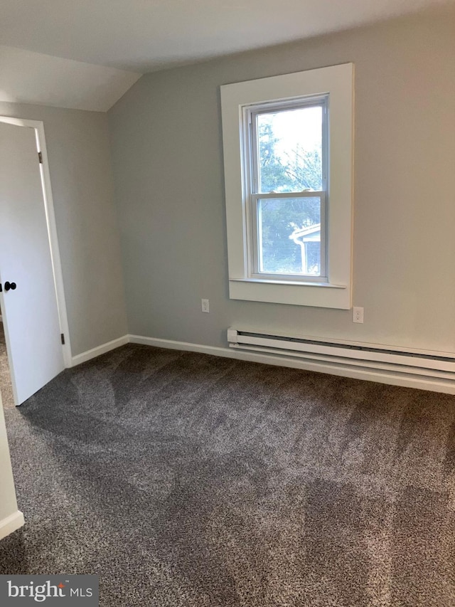 spare room with a baseboard radiator, baseboards, vaulted ceiling, and dark colored carpet