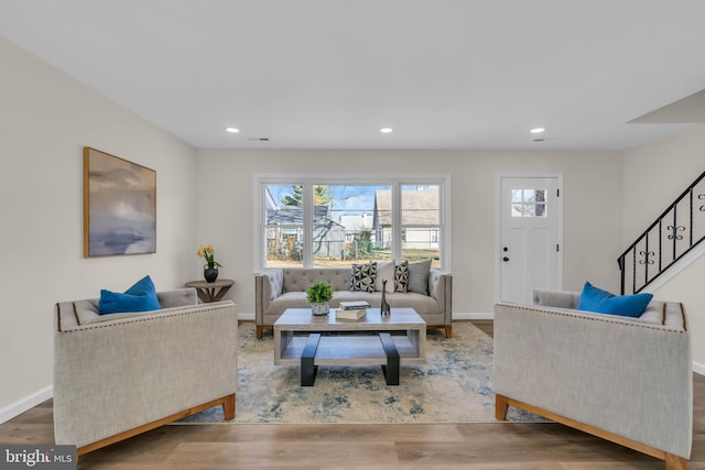 living area with baseboards, stairway, wood finished floors, and recessed lighting