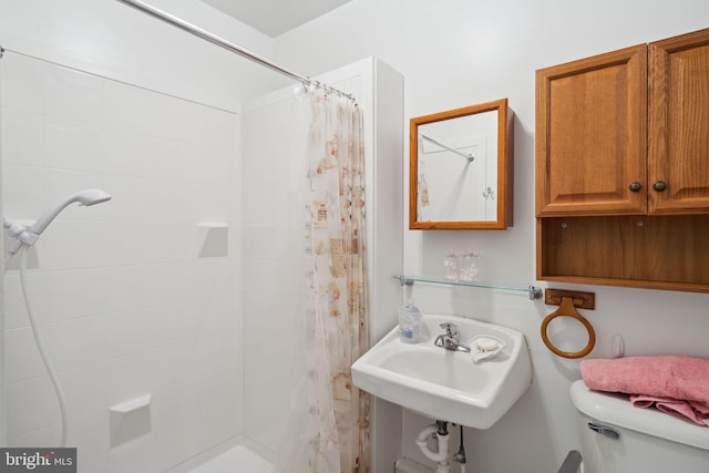 bathroom featuring a sink, a tile shower, and toilet