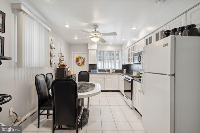 kitchen featuring light tile patterned flooring, recessed lighting, white appliances, white cabinets, and dark countertops