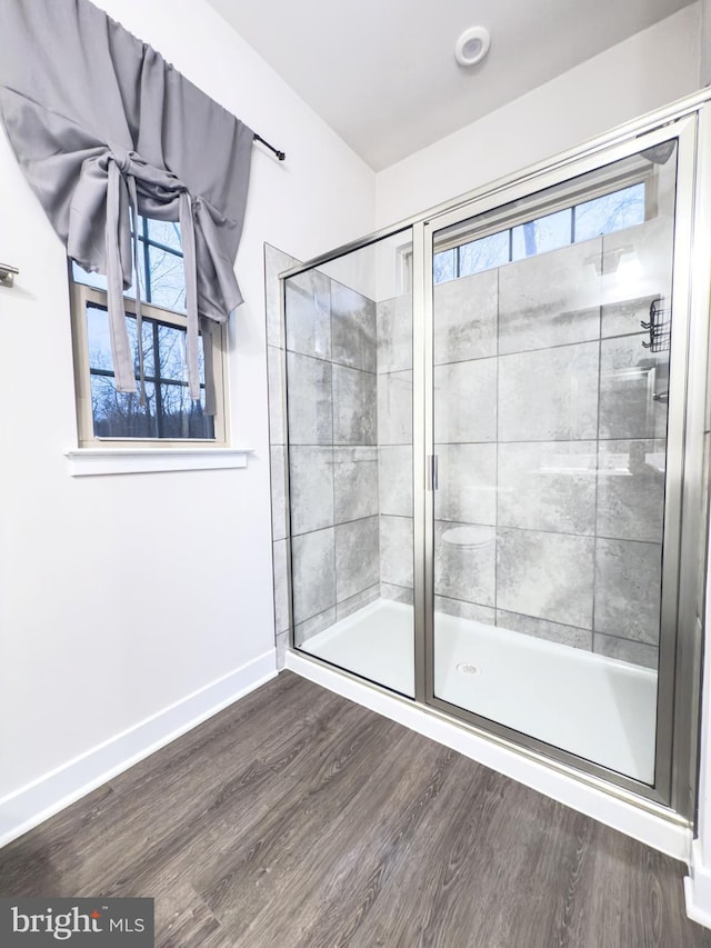 full bath featuring plenty of natural light, a shower stall, and wood finished floors