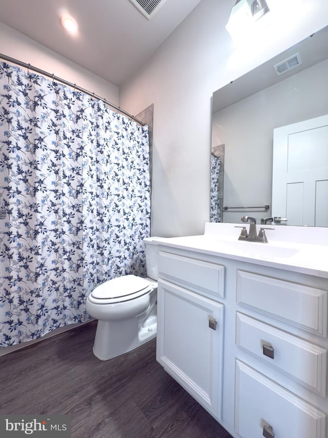 full bath featuring toilet, visible vents, wood finished floors, and vanity