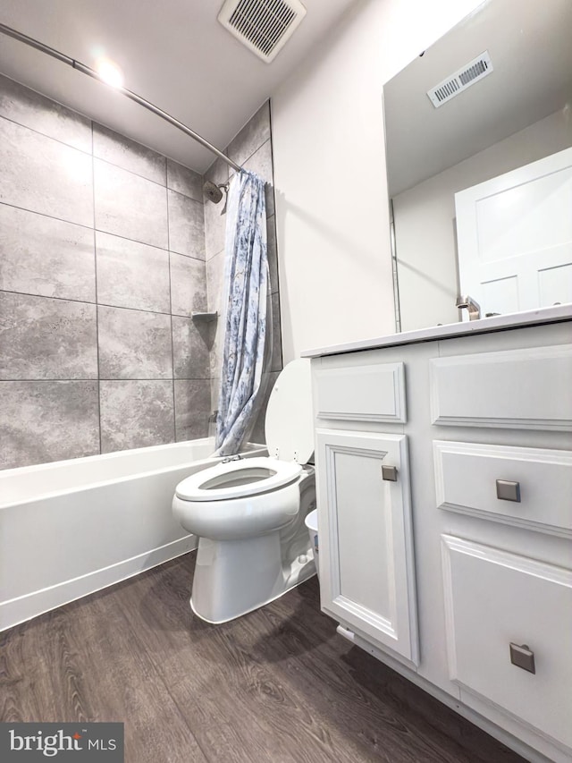 full bath featuring toilet, visible vents, wood finished floors, and shower / tub combo with curtain