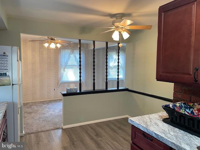 kitchen with a ceiling fan, baseboards, wood finished floors, and freestanding refrigerator