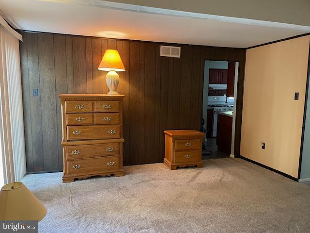 bedroom with light carpet, wood walls, and visible vents