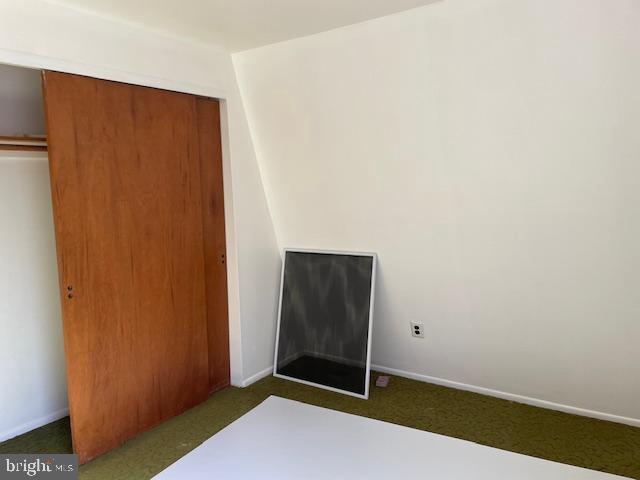 unfurnished bedroom featuring carpet floors, a closet, and baseboards