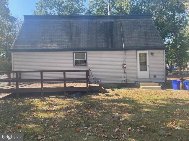 rear view of house with entry steps, a shingled roof, a lawn, and a wooden deck