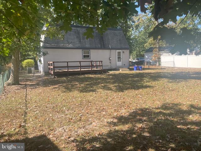 back of house with a deck, a yard, and a fenced backyard