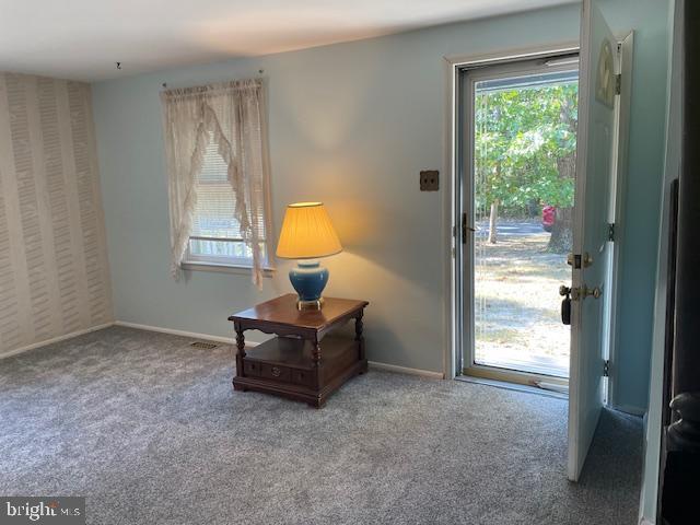 doorway featuring carpet floors and baseboards