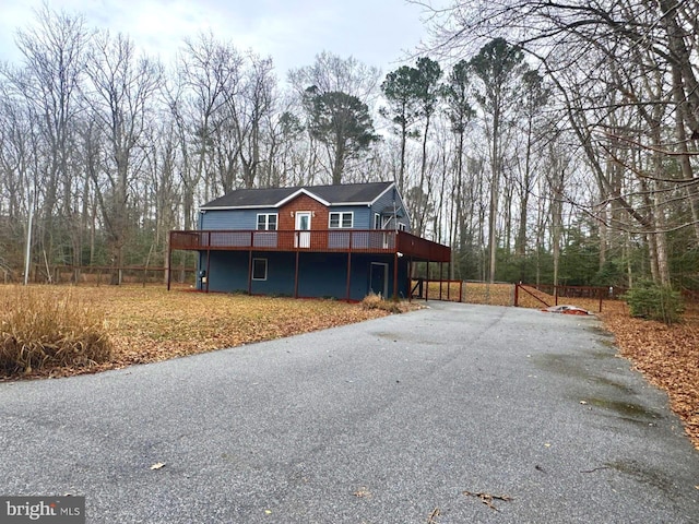 view of front of home featuring driveway, fence, and a wooden deck