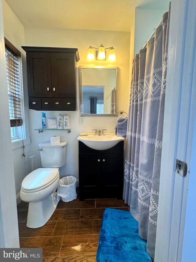 bathroom featuring wood tiled floor, baseboards, vanity, and toilet