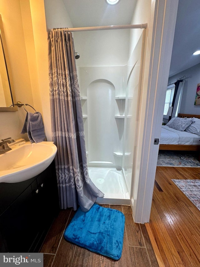 ensuite bathroom featuring ensuite bath, a shower stall, vanity, and wood finished floors