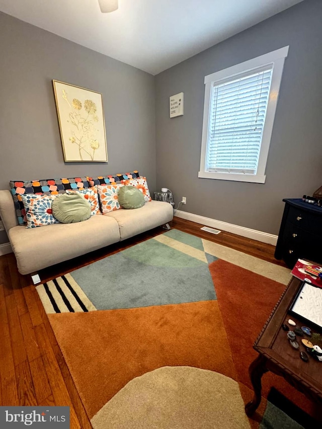 living area featuring wood finished floors, visible vents, and baseboards