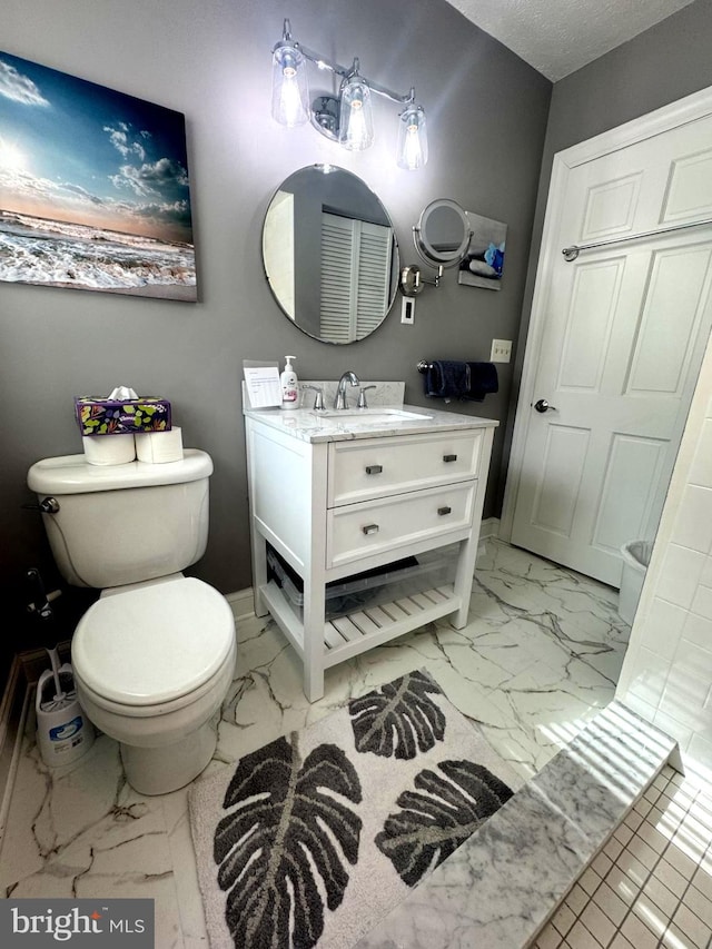 bathroom with marble finish floor, vanity, toilet, and a textured ceiling