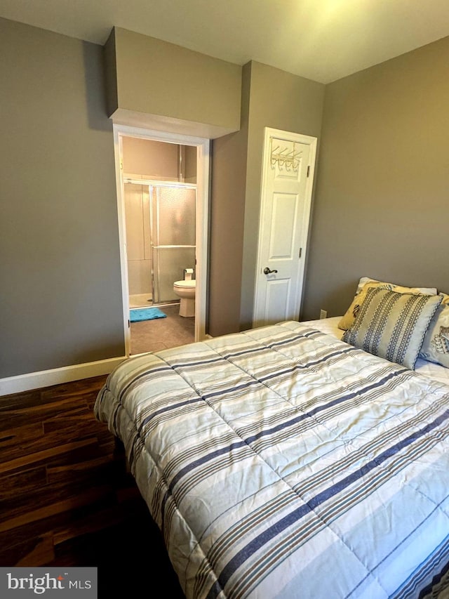 bedroom with baseboards, wood finished floors, and ensuite bathroom