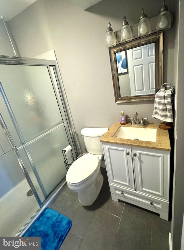 bathroom featuring toilet, a shower stall, vanity, and tile patterned floors