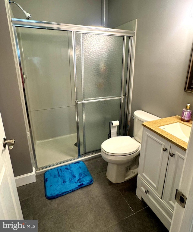 bathroom featuring toilet, a shower stall, vanity, and tile patterned floors