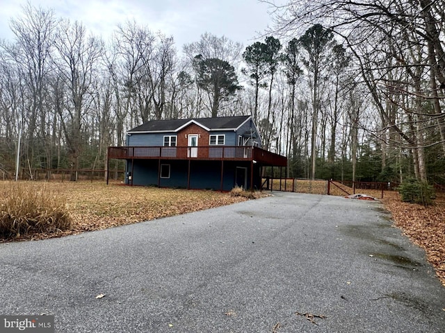 view of front of home with driveway, fence, and a deck