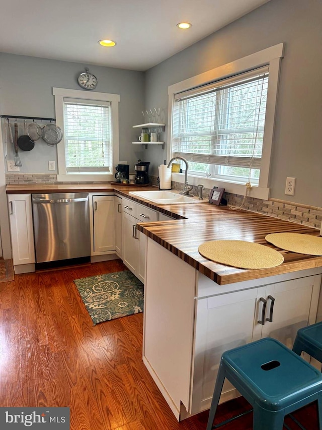 kitchen with dark wood-style flooring, a sink, white cabinets, a wealth of natural light, and dishwasher