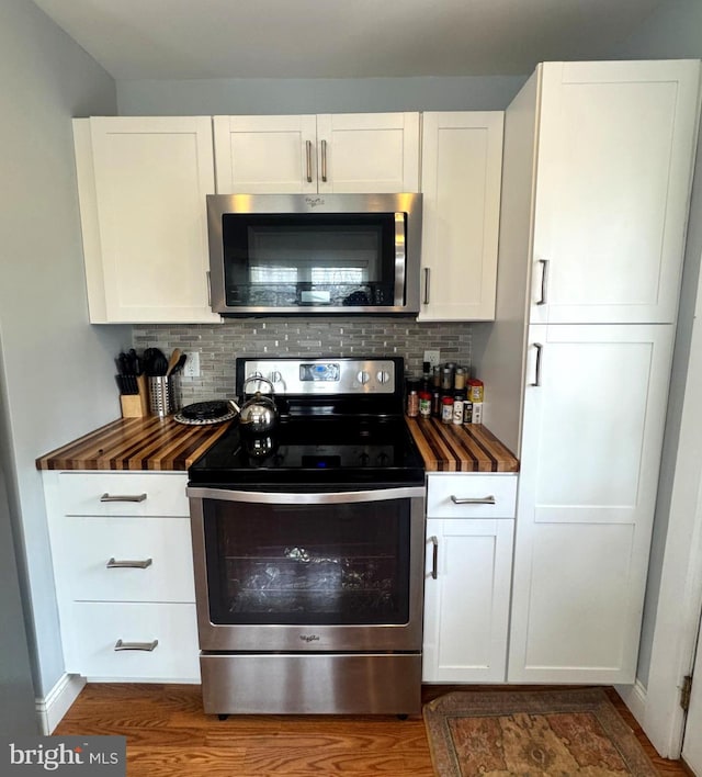 kitchen with white cabinets, stainless steel appliances, wooden counters, and decorative backsplash