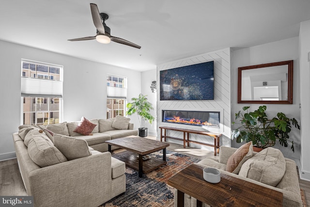 living room featuring a large fireplace, dark wood finished floors, and baseboards