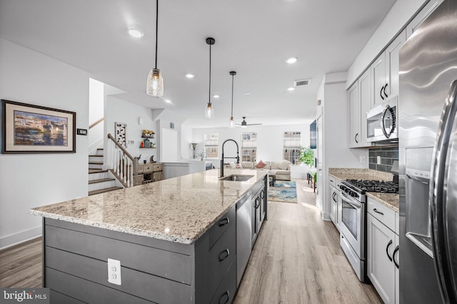 kitchen featuring a sink, visible vents, appliances with stainless steel finishes, light wood-type flooring, and a large island with sink