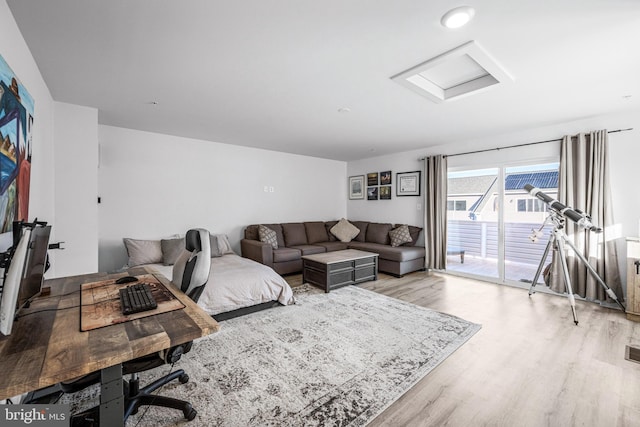 living area featuring attic access, light wood-type flooring, and visible vents