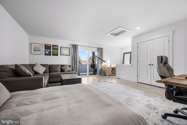 bedroom featuring wood finished floors, baseboards, access to exterior, a closet, and attic access