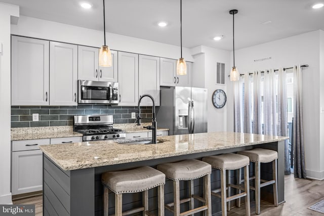 kitchen featuring wood finished floors, a sink, visible vents, appliances with stainless steel finishes, and backsplash