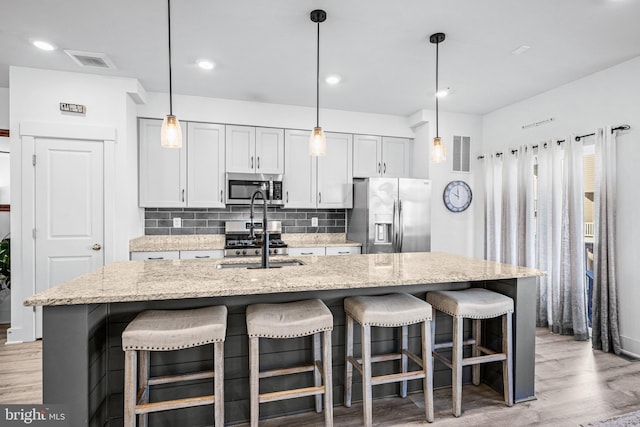 kitchen featuring an island with sink, visible vents, appliances with stainless steel finishes, and a sink