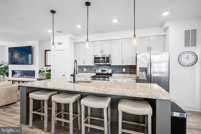 kitchen featuring light wood-style flooring, stainless steel appliances, a sink, visible vents, and tasteful backsplash