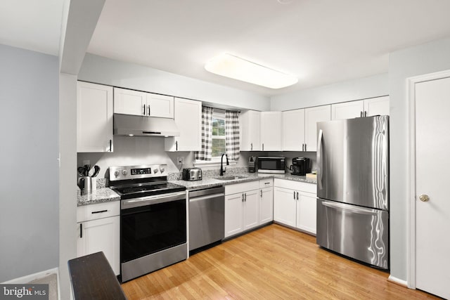 kitchen with stainless steel appliances, a sink, white cabinetry, and under cabinet range hood