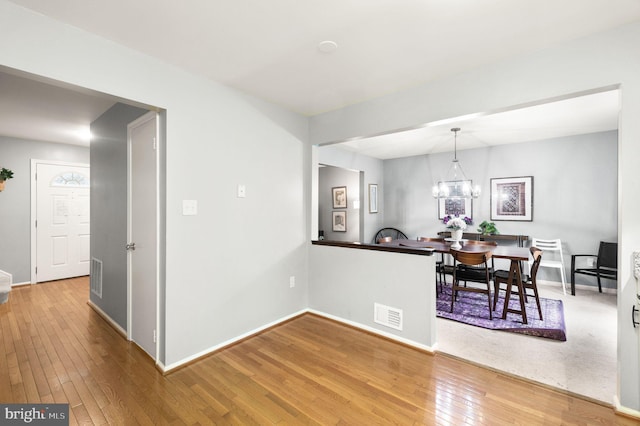 dining area featuring a chandelier, visible vents, baseboards, and hardwood / wood-style flooring