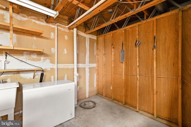 basement with a sink and white refrigerator