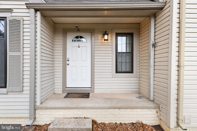 doorway to property featuring roof with shingles