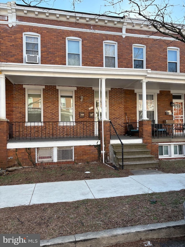 townhome / multi-family property featuring cooling unit, covered porch, and brick siding