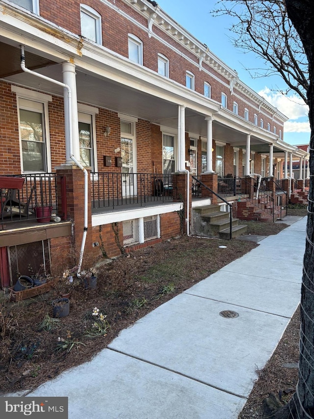 exterior space with a porch and brick siding