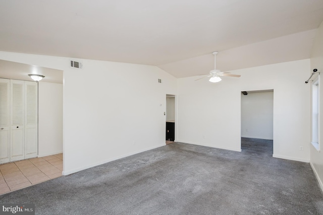 carpeted spare room with baseboards, visible vents, ceiling fan, tile patterned flooring, and vaulted ceiling