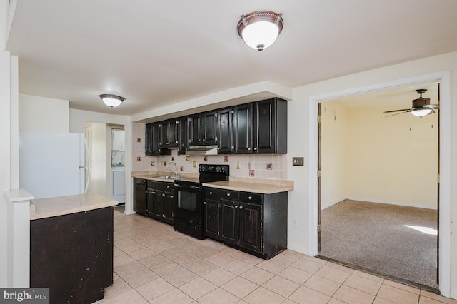 kitchen featuring black / electric stove, washer / dryer, freestanding refrigerator, light countertops, and dark cabinets